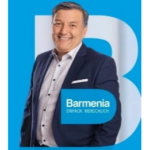 Barmenia Portrait eines lächelnden Mannes im Blazer vor blauem Hintergrund