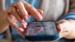 Hände bedienen ein Smartphone mit App-Übersicht.